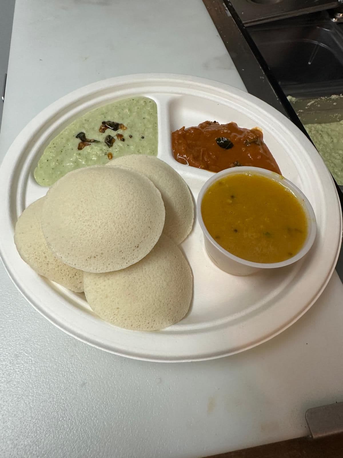 Four idli with sambar and two chutneys, from Madhu Idiyappa Kadai